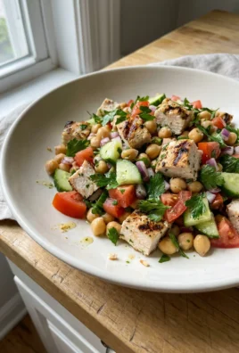 Overhead view of chicken and chickpea salad with visible chunks of tomato and cucumber.
