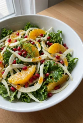 A fork taking a bite of fennel and pomegranate salad from a white plate.