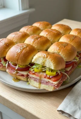 A top-down view of Italian sliders being drizzled with vinaigrette before serving.