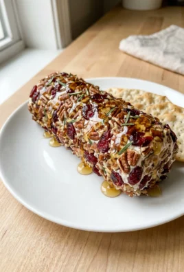 A close-up of the sliced cranberry pecan goat cheese log served with apple slices and crackers.