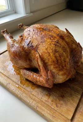 A finished dry brined roast turkey on a white platter, ready to be carved.