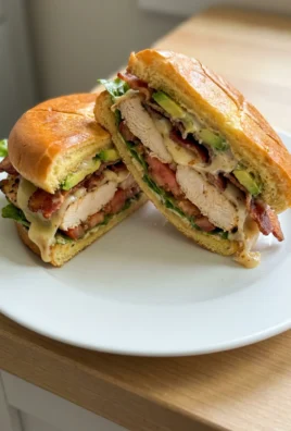 A close-up of a cut grilled chicken sandwich with visible layers.