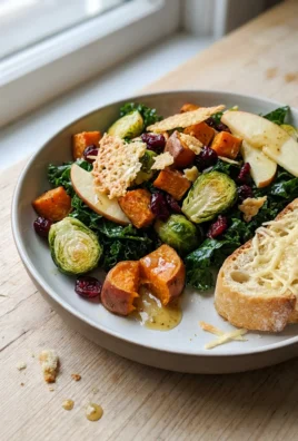 A close-up shot of the finished kale salad in a white bowl, showing all the colorful ingredients.