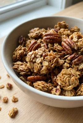 Golden brown maple pecan granola spread out on a baking sheet to cool.
