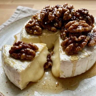 Close-up of gooey baked brie with crunchy maple-glazed walnuts on top.