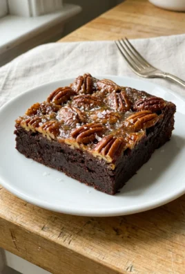 Several pecan pie brownies stacked on parchment paper, showing the gooey topping and fudgy base.