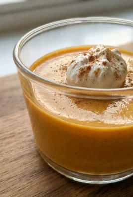 A close-up view of a spoon scooping into a perfectly smooth pumpkin spice panna cotta.