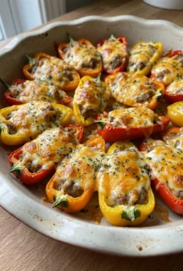 A close-up shot of baked sausage stuffed mini peppers with melted cheese topping.