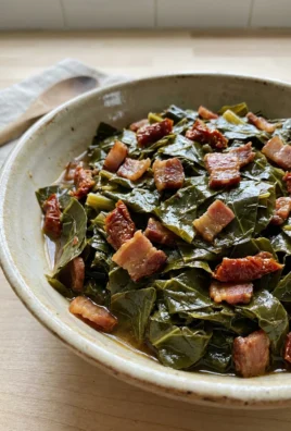 A close-up shot of cooked collard greens with pieces of bacon in a white bowl.