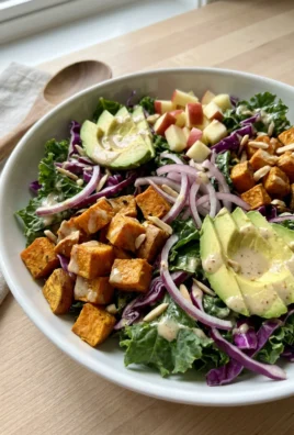A close-up of the sweet potato kale salad showing the creamy almond dressing and toppings.