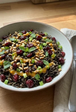A spoonful of wild rice salad with orange vinaigrette being lifted from a serving bowl.