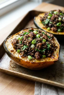 A close-up of a baked acorn squash half filled with sausage and wild rice.
