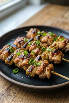 A close-up of grilled yakitori chicken skewers on a simple serving platter.